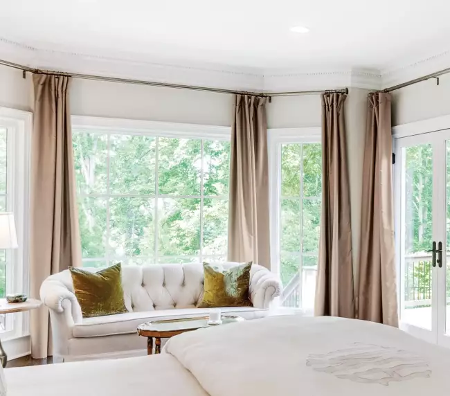 Bright bedroom interior with large French aluminium windows and glass doors, offering a serene garden view.