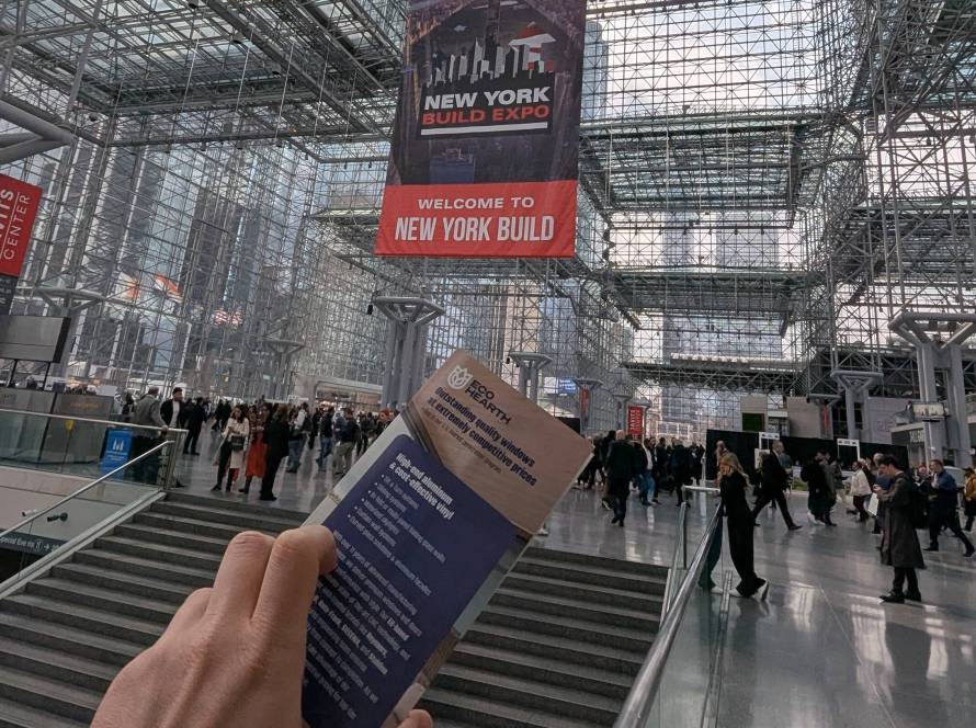 Hand holding expo guide at New York Built Expo inside modern glass convention center