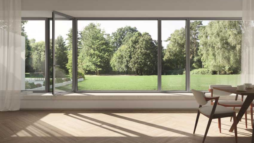 Spacious dining area with big aluminium windows offering an open view of a lush green garden and natural light.