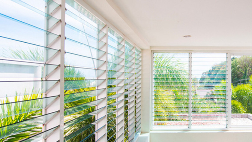 Bright room with fixed aluminium louver windows opening to a tropical garden, stylish and energy-efficient.