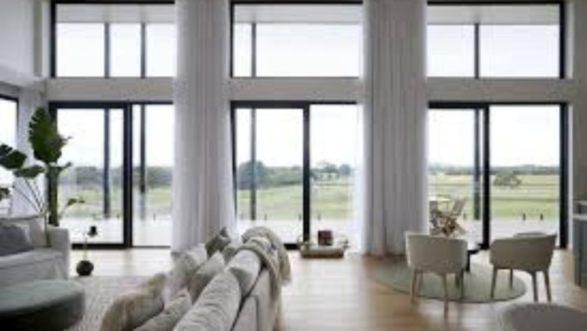 Modern living room with floor-to-ceiling triple glazed aluminium windows overlooking scenic countryside views.