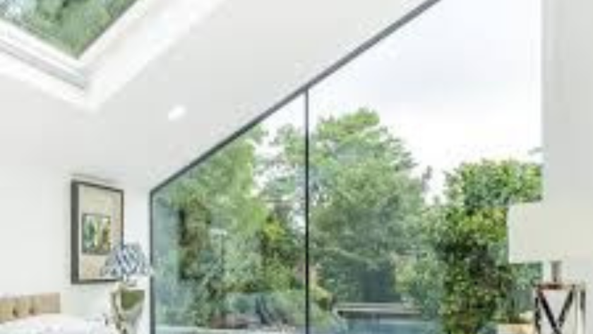 Bright bedroom with floor-to-ceiling slimline aluminium windows and skylight, blending indoor space with nature.