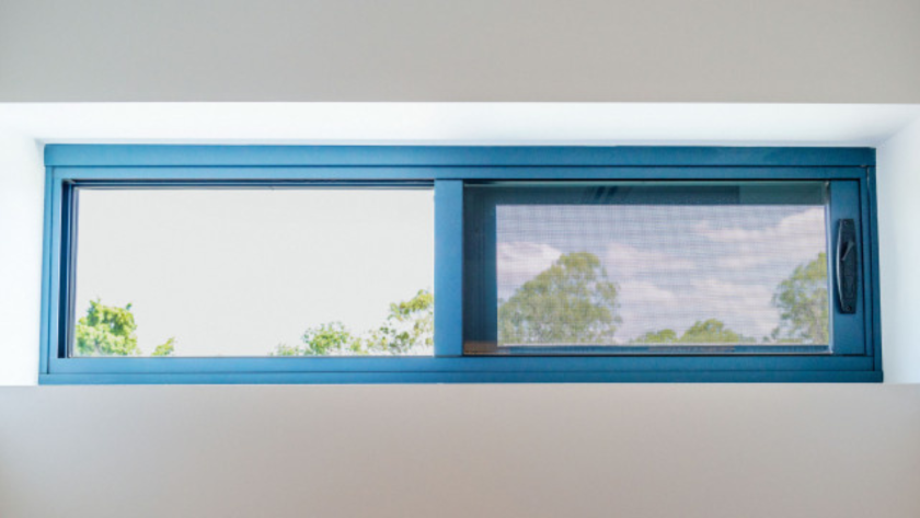 Horizontal small aluminium window with mesh screen, offering ventilation and natural light in a modern interior.