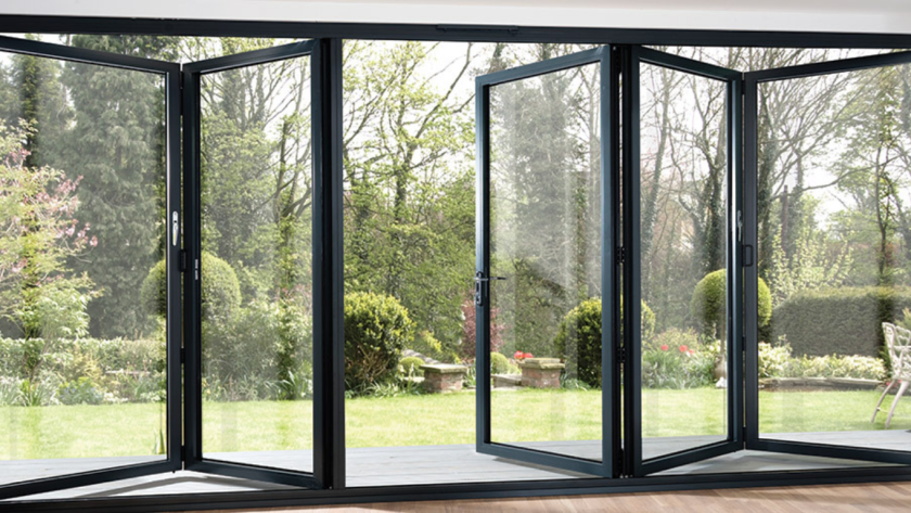 Open aluminium bifold windows connecting a bright indoor space with a lush green garden, perfect for airflow.