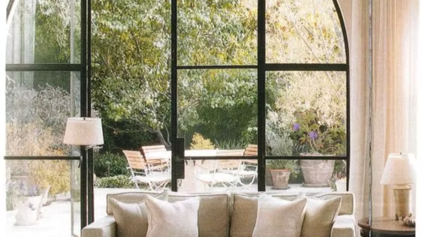 Elegant arched aluminium windows with aluminum around windows, framing a view of a bright garden space.