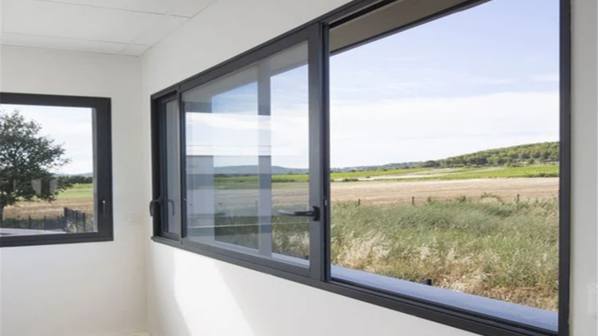 Modern interior showcasing sleek soundproof aluminium windows with black frames overlooking greenery.