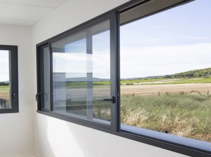 Modern interior showcasing sleek soundproof aluminium windows with black frames overlooking greenery.