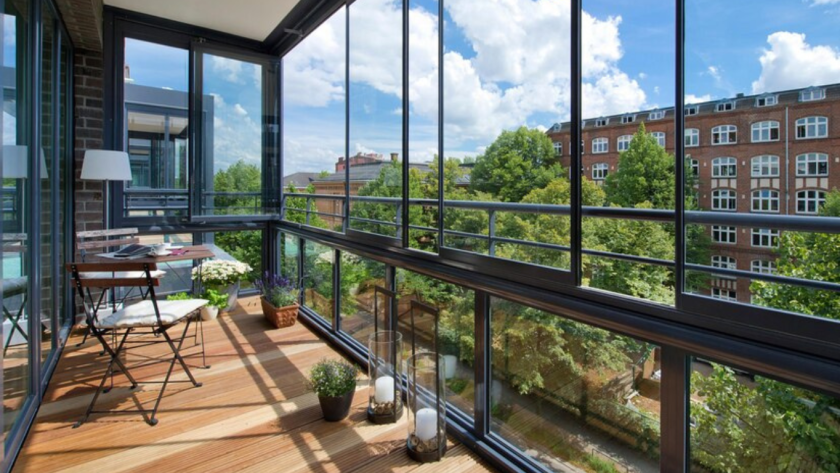 Enclosed balcony with floor-to-ceiling aluminium balcony windows, offering panoramic city and garden views.