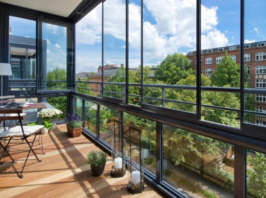 Enclosed balcony with floor-to-ceiling aluminium balcony windows, offering panoramic city and garden views.