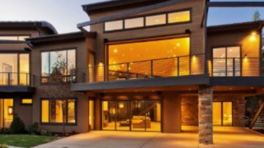 Modern home exterior with large bronze aluminium windows and warm interior lighting, featuring anodised finish.