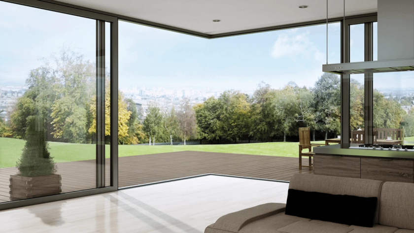 Panoramic view through aluminium corner window overlooking a spacious wooden deck and green landscape with trees and distant city skyline.
