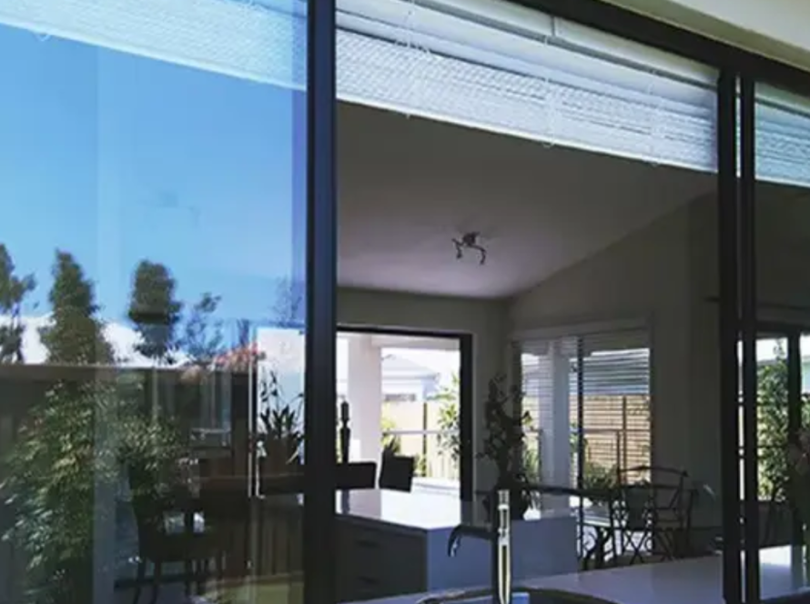 Kitchen view through large aluminium frame glass window with clear exterior reflections