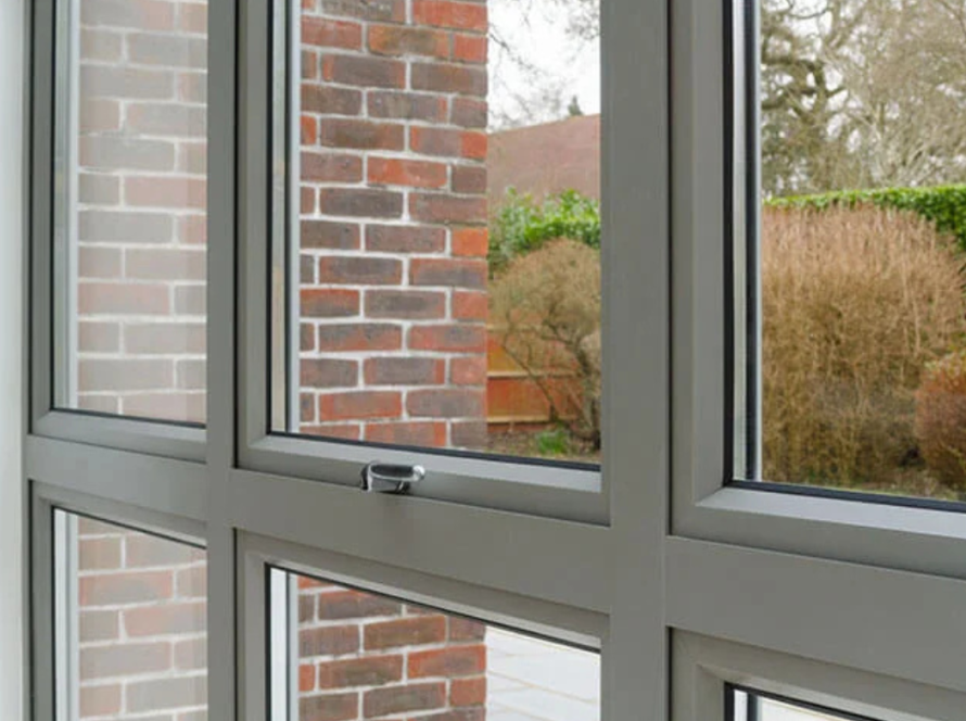 Close-up of grey powder coated aluminium windows framing a garden view, blending modern design with durability.