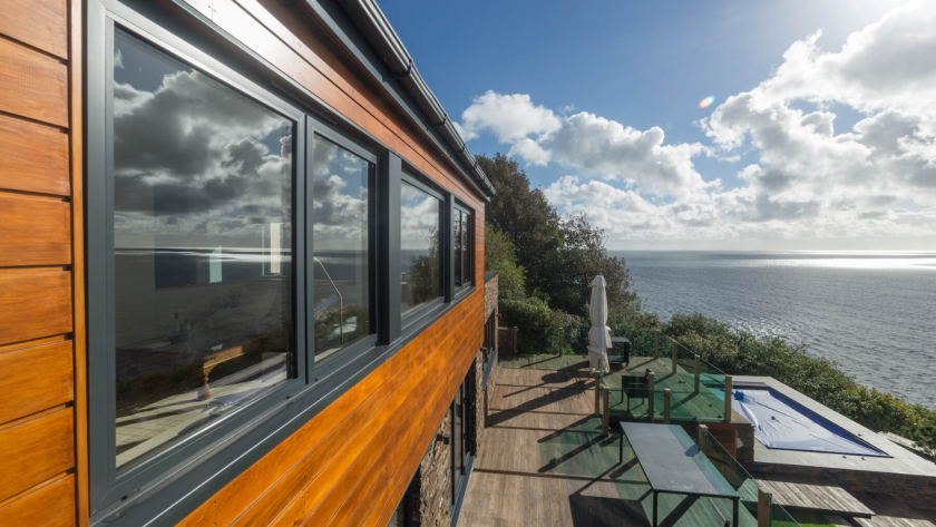Sleek modern aluminium windows reflecting ocean views on a contemporary coastal home
