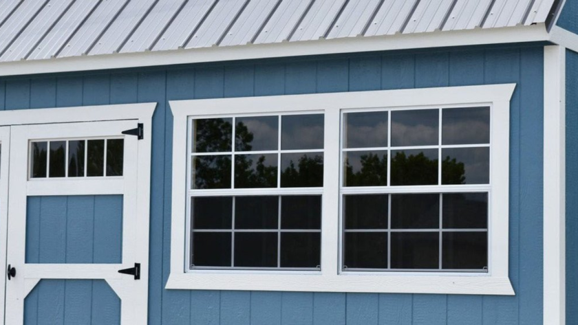 Durable aluminium shed windows installed on a blue storage shed