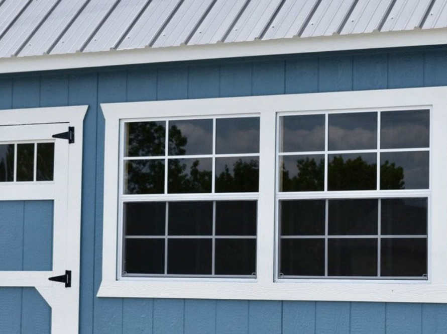 Durable aluminium shed windows installed on a blue storage shed