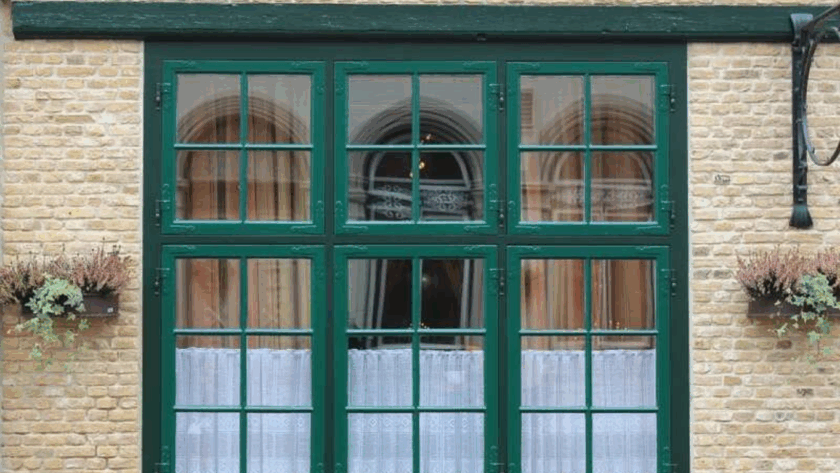 Classic green 30 x 36 casement window with divided panes on a brick exterior wall