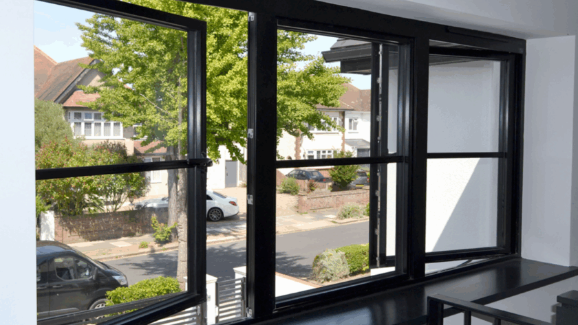 Modern black casement windows opened partially, showing stylish aluminum frames and clear glass, overlooking a suburban neighborhood.