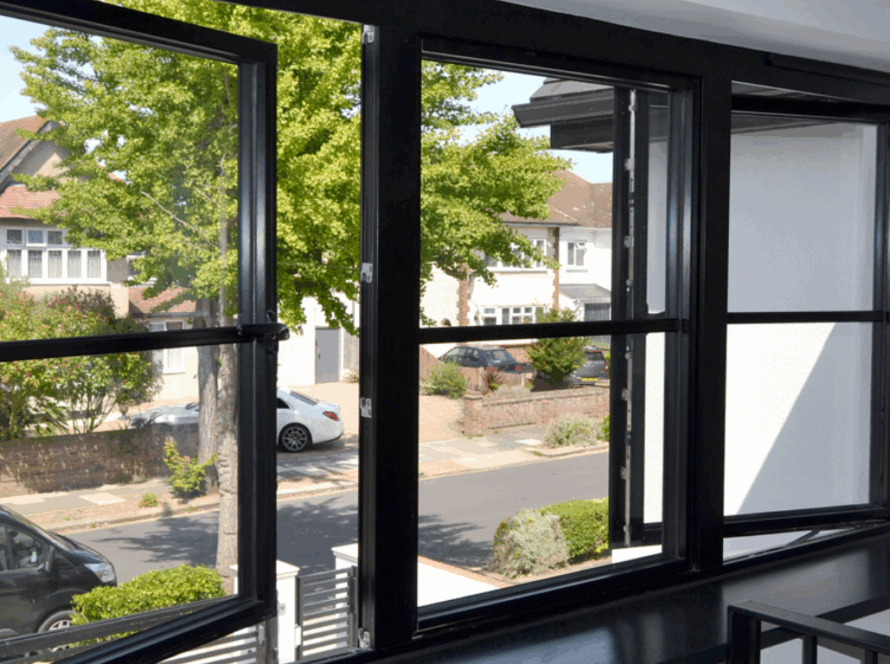 Modern black casement windows opened partially, showing stylish aluminum frames and clear glass, overlooking a suburban neighborhood.