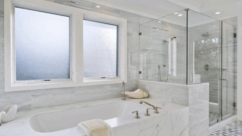 Elegant bathroom interior with privacy glass casement windows above a luxurious marble bathtub