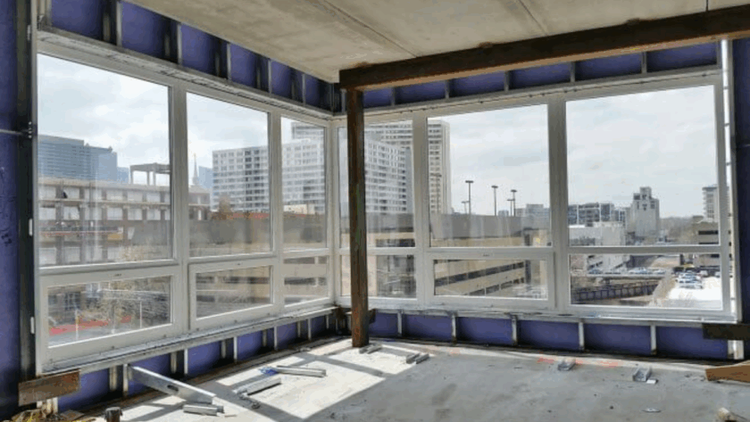 Large commercial aluminum casement windows installed in a modern building with city skyline views