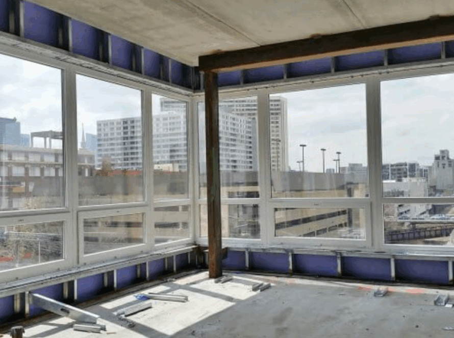 Large commercial aluminum casement windows installed in a modern building with city skyline views