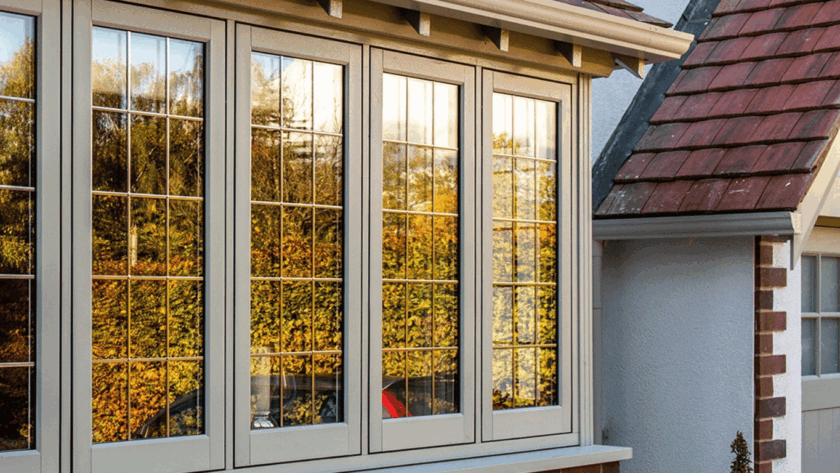 Cream-colored flush uPVC windows with grid detailing reflecting autumn trees, installed in a traditional American home exterior