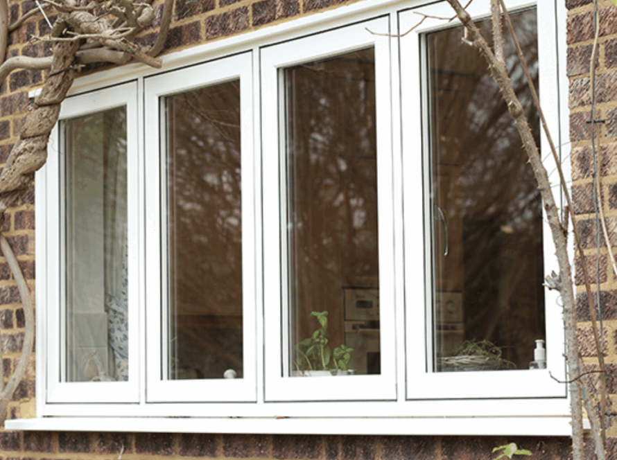 White flush windows installed in a brick exterior wall, surrounded by climbing branches, offering a seamless, modern finish