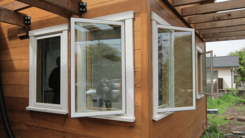 White single casement windows open outward on a wooden house exterior with modern design and clean lines