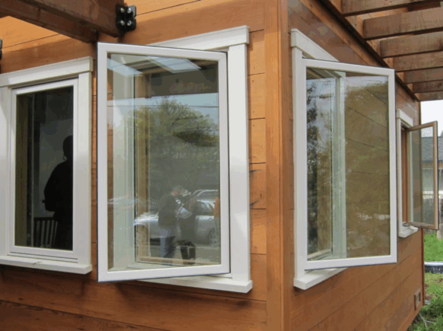 White single casement windows open outward on a wooden house exterior with modern design and clean lines