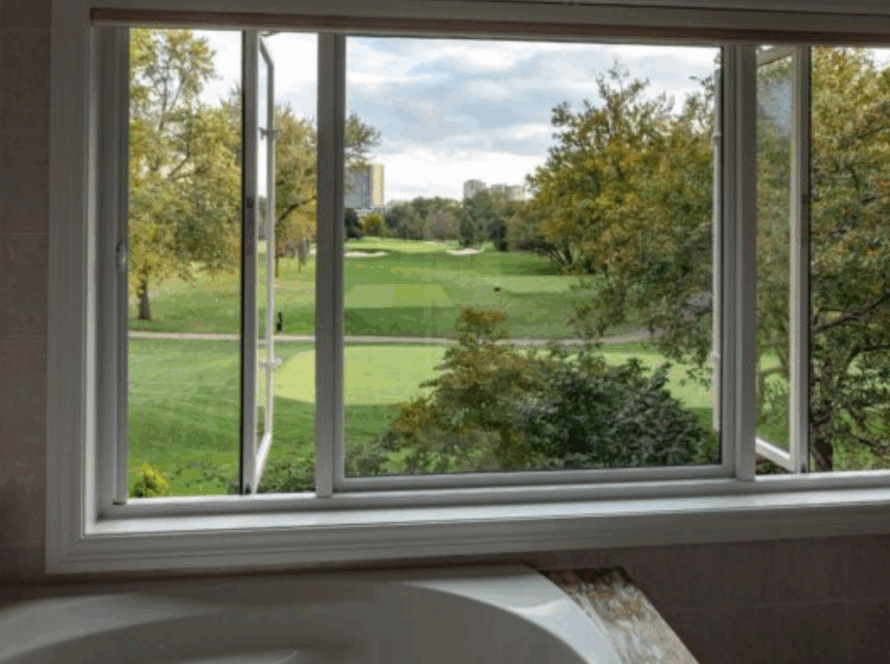 Bathroom window open to a green golf course view with a modern slider replacing the original casement window
