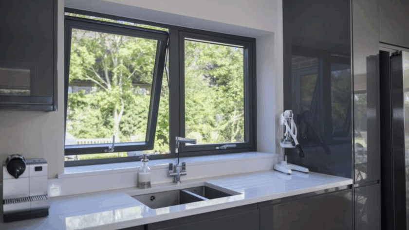 Modern kitchen featuring stylish top hung casement windows overlooking a green backyard