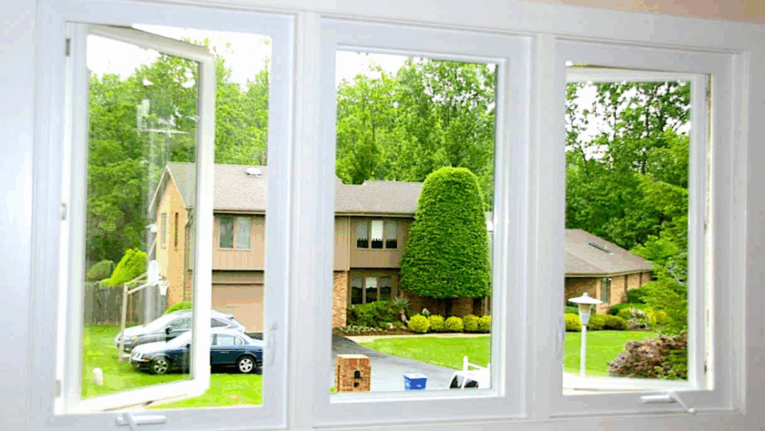 Three white triple casement windows opened wide, showcasing a clear view of a suburban neighborhood and lush greenery
