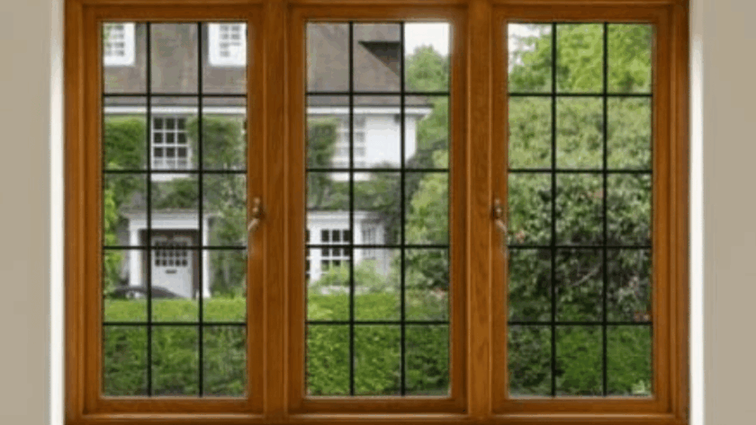 Triple-panel wooden French windows with black grid detailing, offering a view of a classic green garden and white house exterior