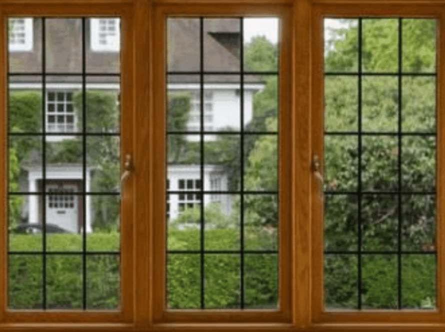 Triple-panel wooden French windows with black grid detailing, offering a view of a classic green garden and white house exterior