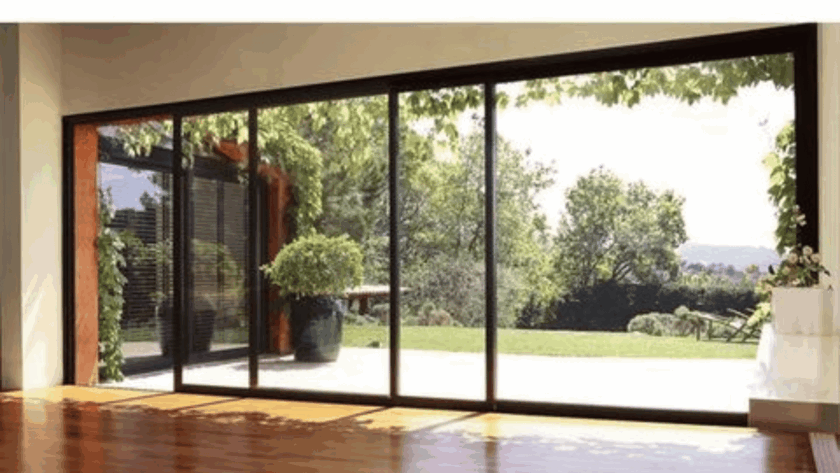 Large aluminium vertical sliding windows with panoramic garden view and slim black frames