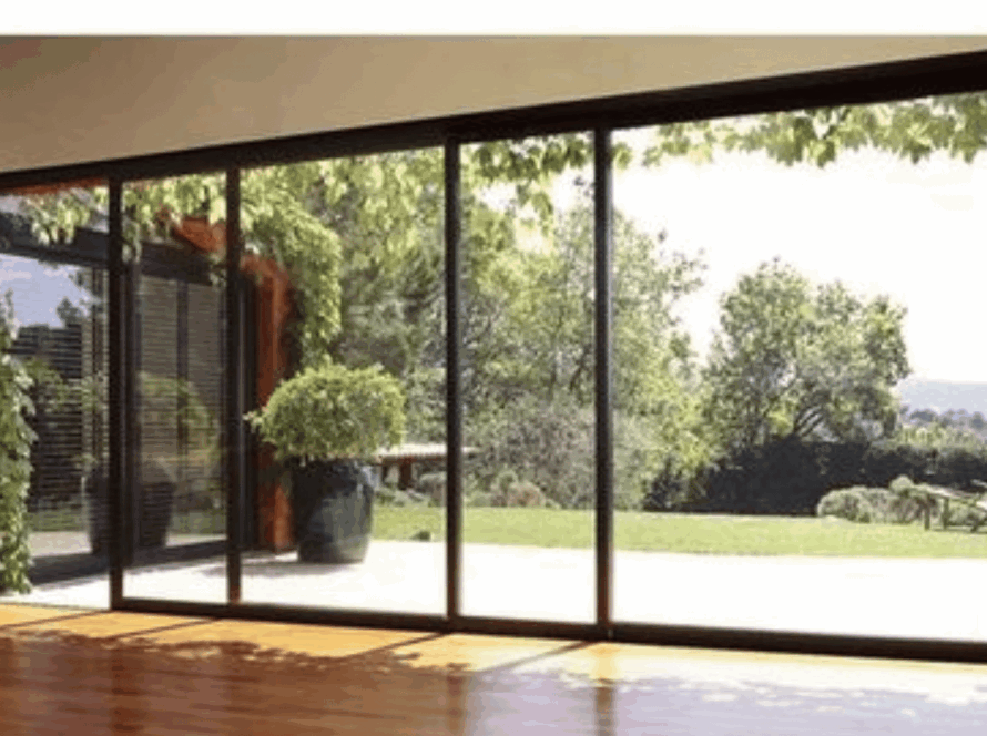 Large aluminium vertical sliding windows with panoramic garden view and slim black frames