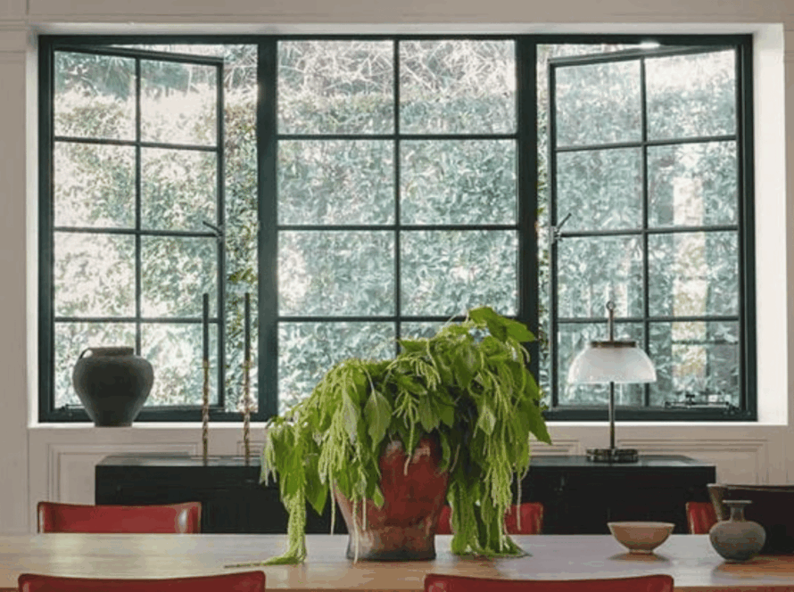 Elegant black aluminum casement windows opening to a lush green garden view