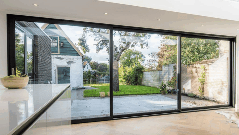 Anodized aluminum sliding windows overlooking a cozy backyard garden and patio