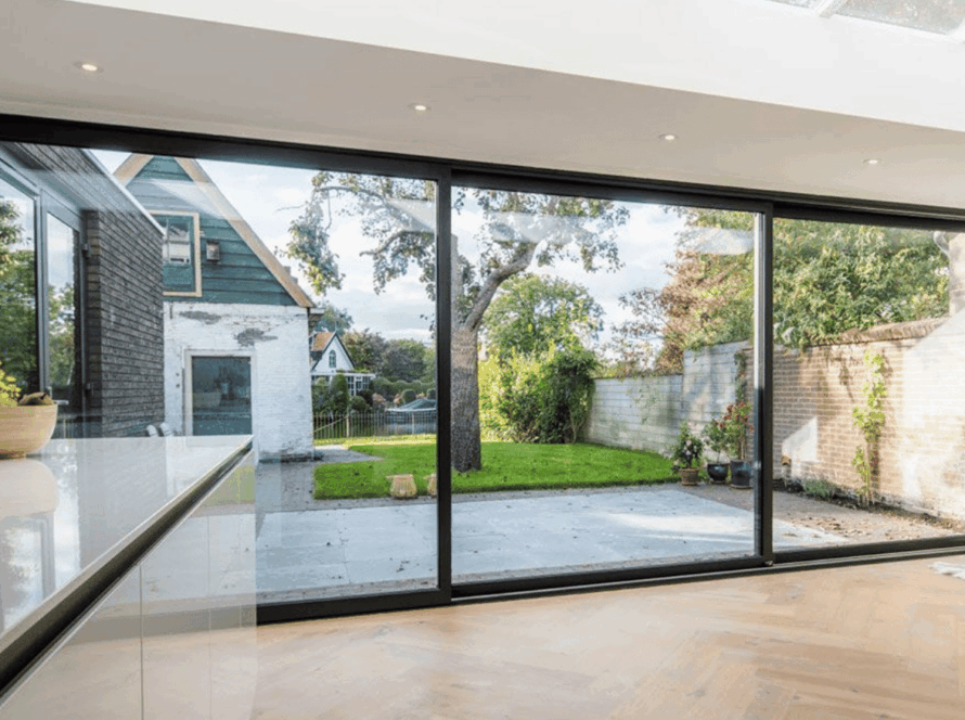 Anodized aluminum sliding windows overlooking a cozy backyard garden and patio