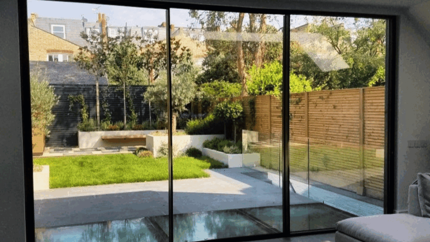Spacious living room with modern black aluminium sliding windows overlooking a lush backyard