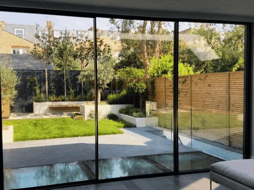 Spacious living room with modern black aluminium sliding windows overlooking a lush backyard