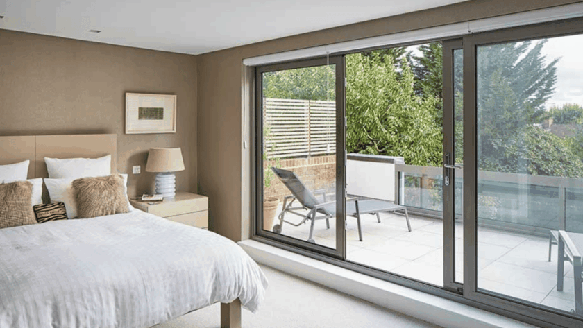 Modern bedroom with elegant sliding windows opening onto a peaceful, private terrace surrounded by greenery
