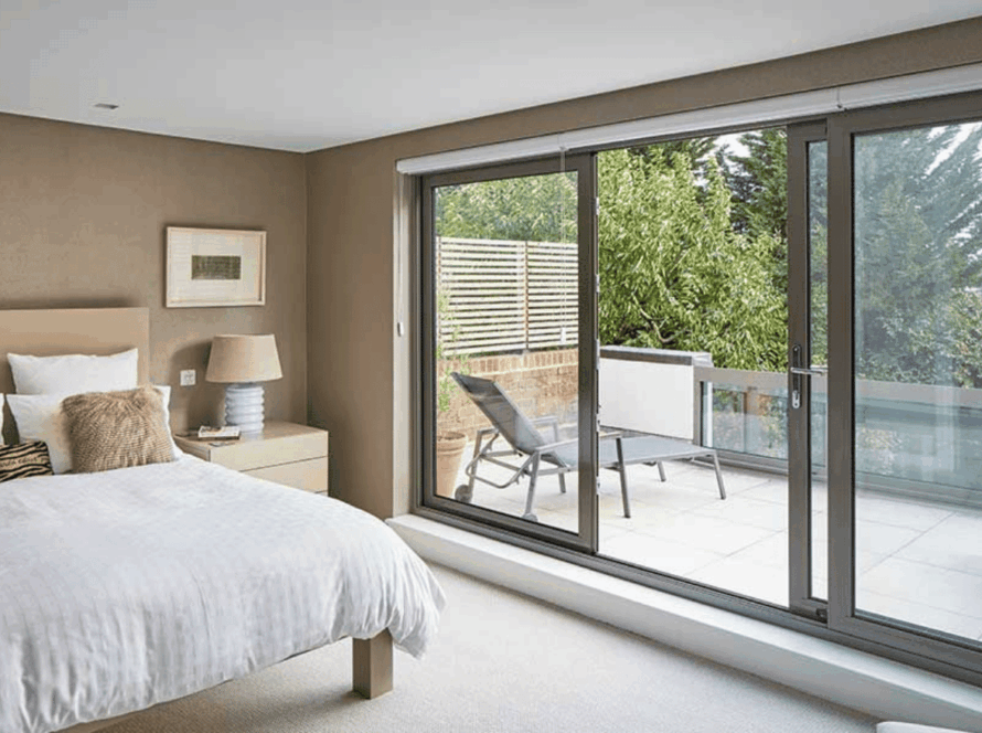 Modern bedroom with elegant sliding windows opening onto a peaceful, private terrace surrounded by greenery