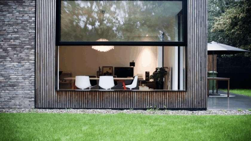 Contemporary home featuring a sleek aluminum upper sliding window seamlessly connecting indoor living space with a lush, green backyard