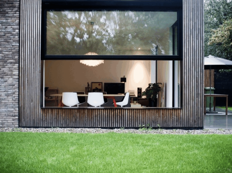 Contemporary home featuring a sleek aluminum upper sliding window seamlessly connecting indoor living space with a lush, green backyard