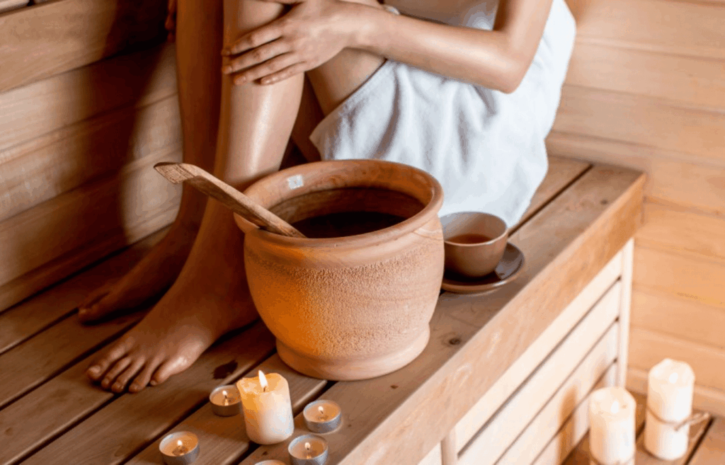 Woman relaxing in a wooden sauna with herbal tea and candles, cozy wellness and spa atmosphere