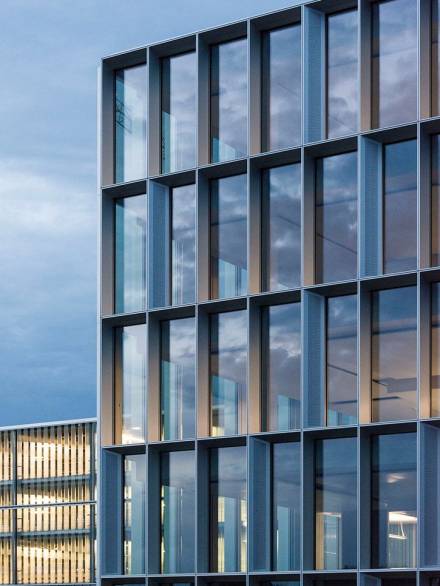 29406b55eb426cefdf9b7b88a1dc8b6f Modern building elevation featuring a curtain wall system with deep aluminum profiles and reflective glazing, emphasizing geometric precision and contemporary design.