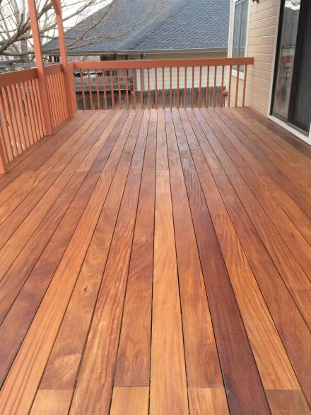 6810579846295b305d39e09174f84ca3 Freshly finished wood decking on a raised backyard patio, showcasing the natural grain and warm tones of the timber, bordered by classic wooden railings.