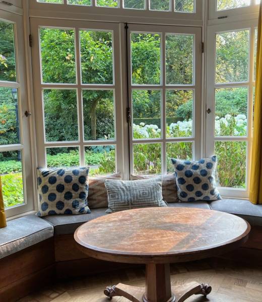 Bay aluminium windows with classic grid-style frames and a built-in bench offering a cozy garden view.